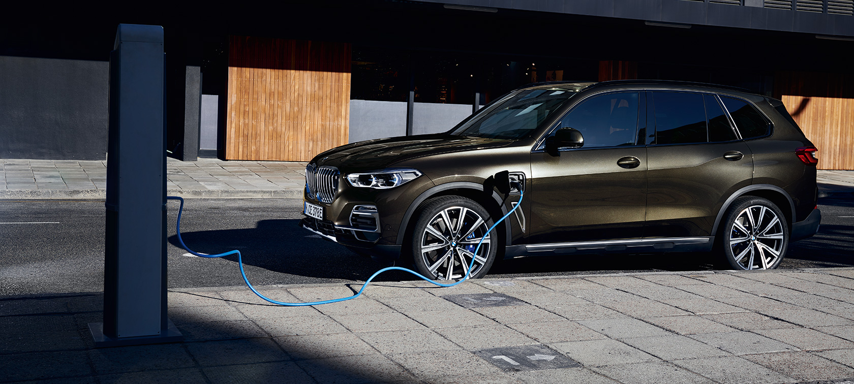 Plug-in hybrid BMW X5 xDrive45e G05 three-quarter side view charging